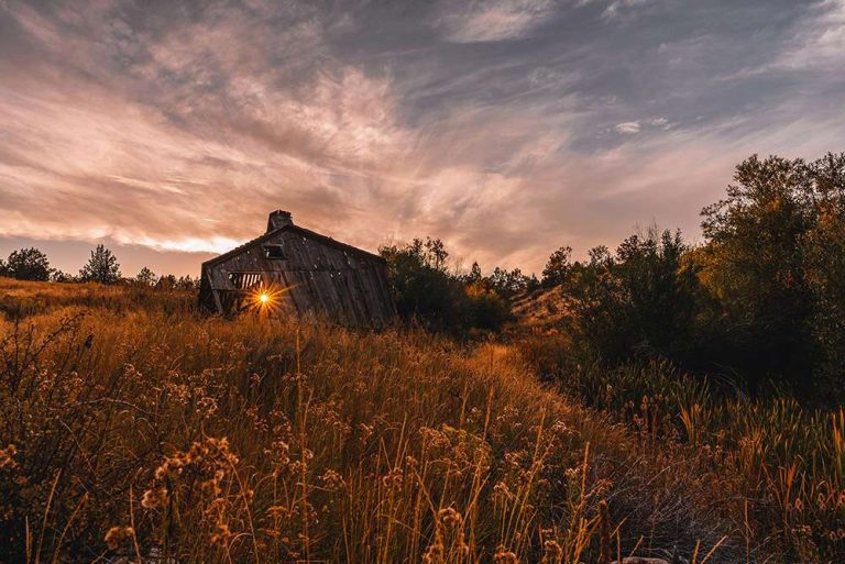 Sun setting through the cracks of an old decaying wood barn