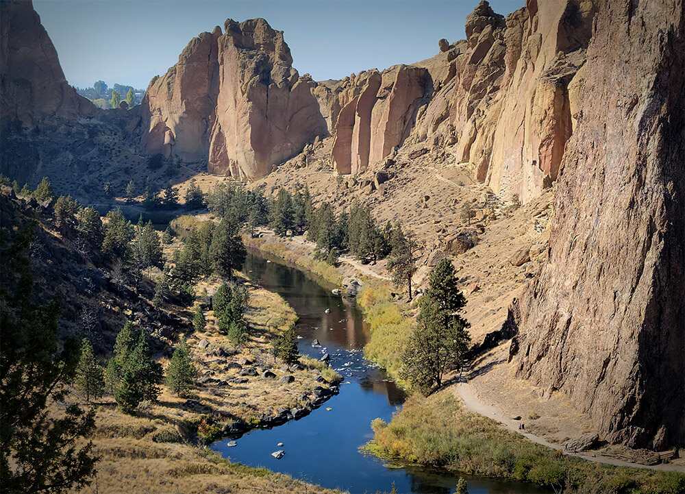 A smaller winding river cuts through dramatic jagged desert cliffs