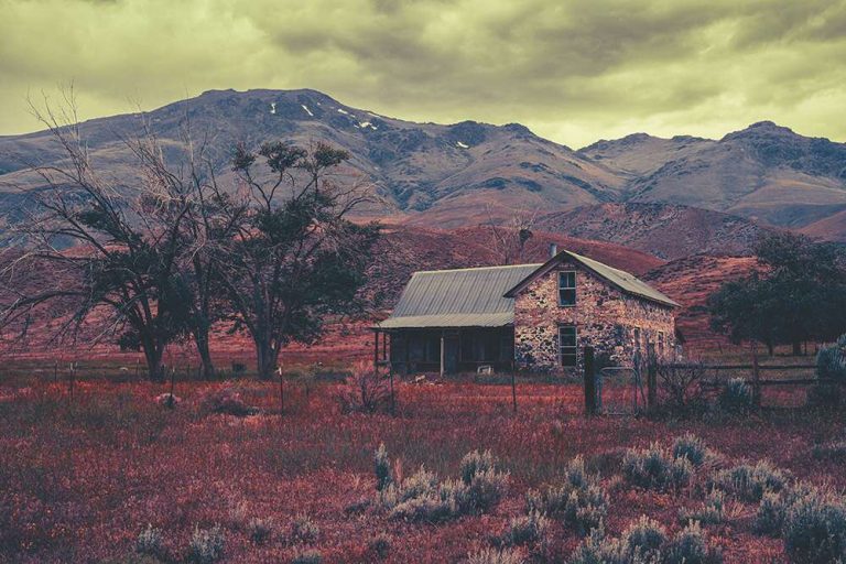 A rustic stone house in Eastern Oregon with fall colors in the grass and hills