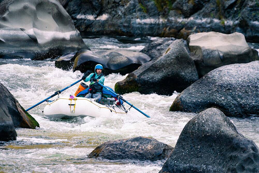 A man whitewater rafting through a rocky Rogue River